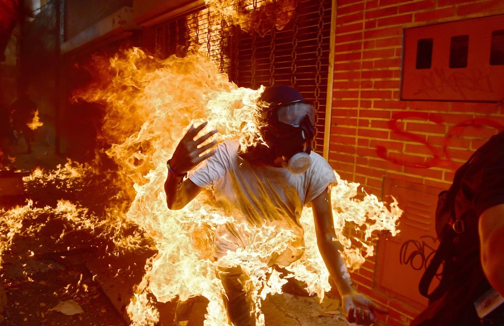 A demonstrator catches fire during clashes with riot police within a protest against Venezuelan President Nicolas Maduro, in Caracas on May 3, 2017. Venezuela's angry opposition rallied Wednesday vowing huge street protests against President Nicolas Maduro's plan to rewrite the constitution and accusing him of dodging elections to cling to power despite deadly unrest. / AFP PHOTO / RONALDO SCHEMIDT
